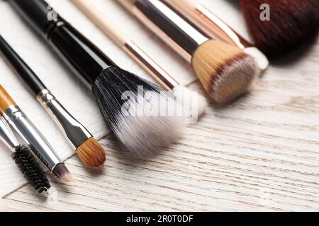 Pulire le spazzole per il trucco con un tovagliolo su un tavolo di legno, closeup Foto Stock