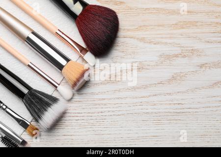 Pulire le spazzole per il trucco con un tovagliolo su un tavolo di legno, piatto. Spazio per il testo Foto Stock