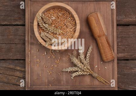 Mortaio, pestello e spighe di grano su tavola di legno, piatto Foto Stock