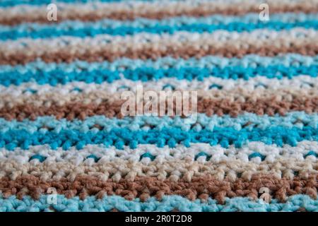 primo piano della coperta a strisce blu, marrone e bianco della nonna, con maglia o uncinetto, questa coperta ti fa pensare alla casa della nonna, è accogliente Foto Stock