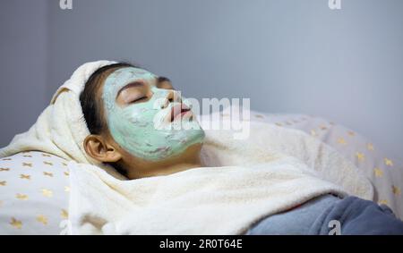 Donna che faceva maschera spa c'era un asciugamano sulla testa. Cura della pelle per ringiovanimento ed eliminazione di imperfezioni, acne, rughe e lenitivo per Foto Stock