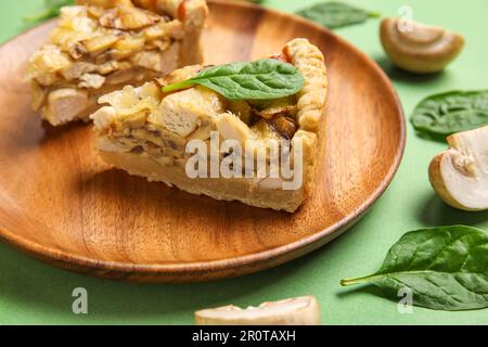 Pezzi di torta di funghi con foglie di spinaci e champignons su sfondo verde Foto Stock