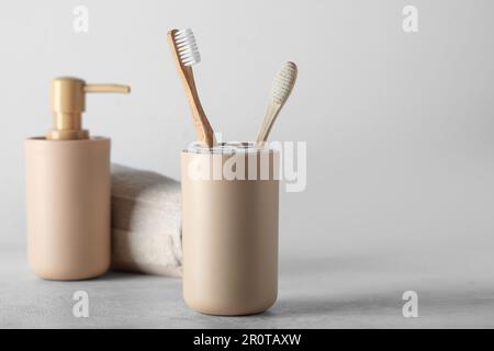 Supporto di spazzolini da denti e accessori da bagno in bambù su tavolo bianco Foto Stock