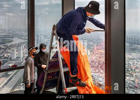 Lavoratori vietnamiti che sostituiscono la finestra di vetro rotta alla torre Landmark 81, ho Chi Minh City, Vietnam Foto Stock