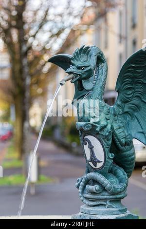 Mitica creatura di basilisk su una fontana pubblica con simbolo della città di Basilea di un crocere bianco e nero, Basilea, Svizzera Foto Stock