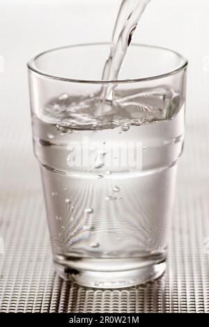 Versando un bicchiere di acqua Foto Stock