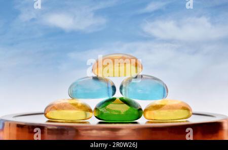 Pila di pietre di vetro colorate con uno sfondo blu cielo e spazio copia. Concetto Zen di equilibrio di vita, tranquillità, feng shui e argomenti correlati. Foto Stock
