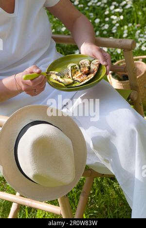 Persona che mangia le zucchine grigliate all'aperto Foto Stock