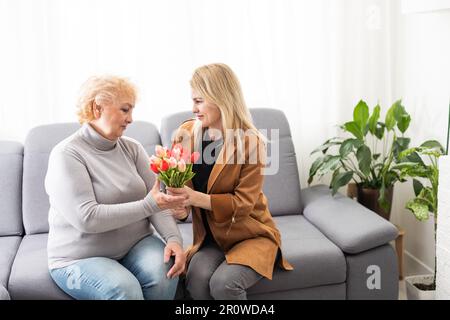 Primo piano immagine madre anziana figlia adulta seduta sul divano interno sorridente cercando in posa per la fotocamera abbracciare si sente felice passare il tempo insieme, concetto Foto Stock