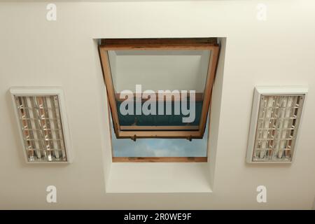 Lucernario aperto sul soffitto inclinato nella camera mansardata, vista dal basso Foto Stock
