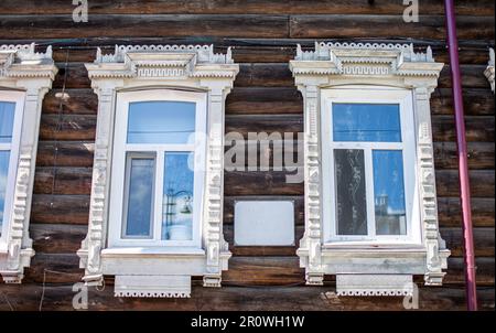 Vecchie case di legno a due piani con finestre nella città di Tomsk, Russia. Alloggi residenziali fatiscenti in cattive condizioni. Foto Stock