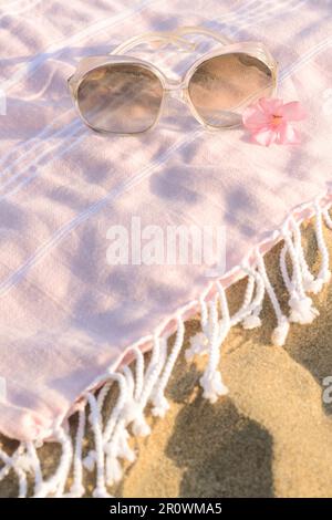 Splendidi occhiali da sole con fiori tropicali su coperta rosa Foto Stock