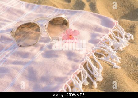 Splendidi occhiali da sole con fiori tropicali su coperta rosa Foto Stock