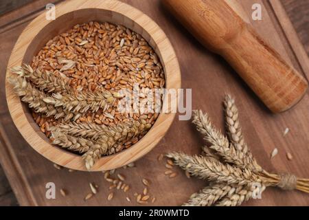 Mortaio, pestello e spighe di grano su tavola di legno, piatto Foto Stock