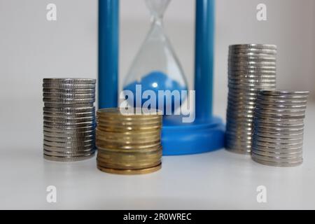 Il vetro e le monete dell'ora come simbolo del valore della foto di stock di concetto di tempo Foto Stock