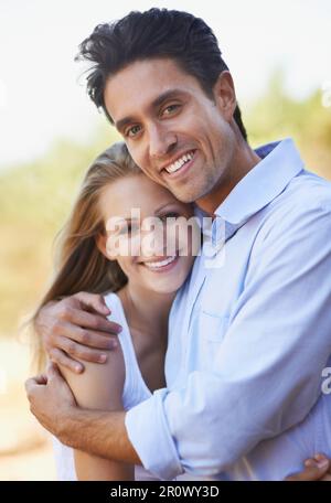 Sicuro nel suo abbraccio. Primo piano di una giovane coppia amorevole che abbraccia intimamente mentre si levano in piedi fuori. Foto Stock