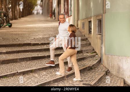 Allegro coppie di viaggiatori maturi camminando attraverso le incantevoli strade di Lisbona Foto Stock