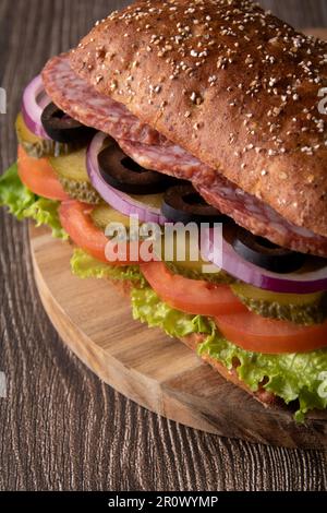 sandwich di salsiccia e verdure sdraiati su un asse di legno Foto Stock