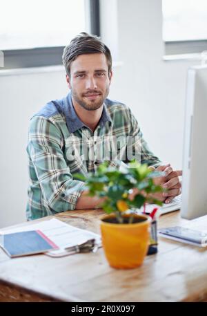 La creatività cresce in questo ufficio. Ritratto di un giovane designer che lavora su un computer in ufficio. Foto Stock