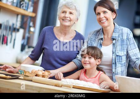 Incollaggio durante la cottura dei biscotti. una famiglia generazionale tre che cuoce insieme. Foto Stock