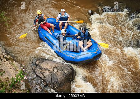 Attraverso le rapide. Scatto ad angolo alto di un gruppo di giovani amici rafting su rapide Foto Stock