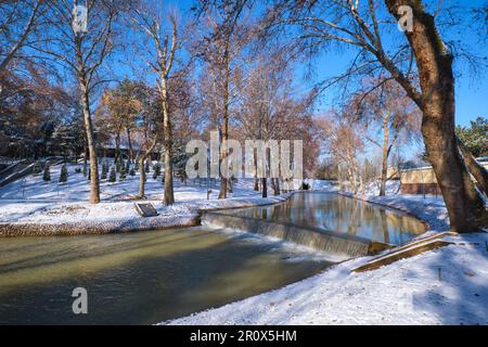 Una vista tranquilla e bucolica lungo un canale del centro con una piccola cascata. Subito dopo una tempesta d'inverno lasciò una luce bianca spolverata di neve fresca. A Tashkent, Foto Stock