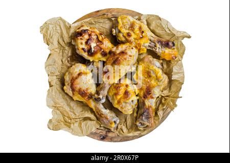 Cosce di pollo al forno su carta Kraft. Isolato su sfondo bianco Foto Stock