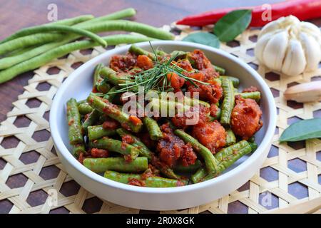 Thai Red curry mescolato fagiolini fritti - cibo asiatico, in tailandese chiamato Pad Prik King sul tavolo di legno a vista ravvicinata Foto Stock