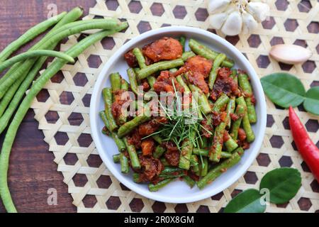 Thai Red curry mescolato fagiolini fritti - cibo asiatico, in tailandese chiamato Pad Prik King su tavolo di legno Foto Stock