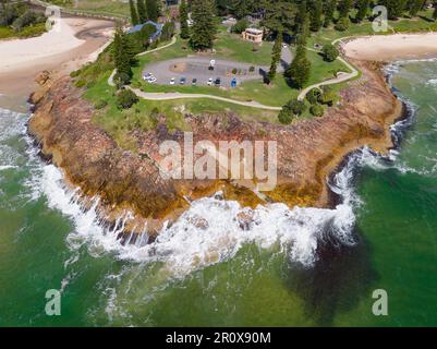 Vista aerea delle onde che si infrangono su un promontorio roccioso con un parcheggio in cima a South West Rocks nel nuovo Galles del Sud, Australia Foto Stock