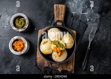 Papas arrugadas Isole Canarie patate rugose con salse verdi e rosse servite in una padella. Sfondo nero. Vista dall'alto. Foto Stock
