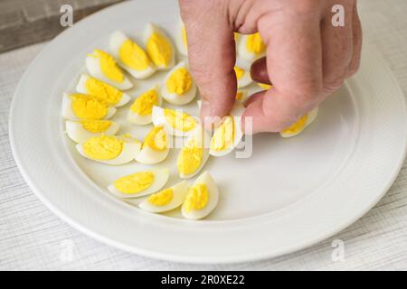 Le mani collocano uova di quaglia su un piatto per colazione, brunch o buffet di festa, focus selezionato, profondità di campo ristretta Foto Stock