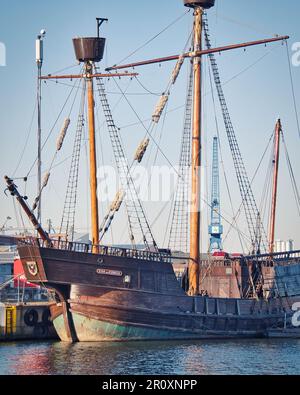 Una grande nave pirata in legno è ancorata in modo sicuro a un molo affollato, circondato da altre navi Foto Stock