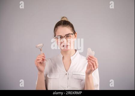 Medico estetista che tiene gouache raschietto e rullo. Foto Stock