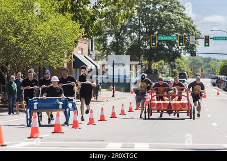 Lawrenceville, GA / USA - 22 aprile 2023: Due squadre spingono i letti lungo una strada cittadina come parte della Family Promise Bed Race, un evento di beneficenza fundraiser. Foto Stock