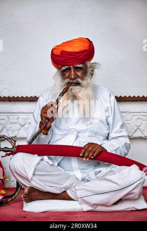 Il vecchio uomo indiano fuma hookah (pipa d'acqua) nel forte di Mehrangarh Foto Stock