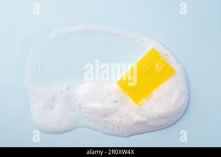 Spugna detergente e schiuma saponata su sfondo blu. Foto Stock