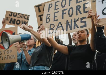 Da sotto folla di diversi manifestanti in abiti casual in piedi con cartelloni in cartone e altoparlante durante la dimostrazione contro la crisi finanziaria Foto Stock