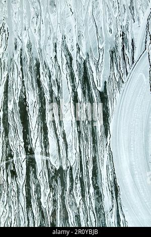 Gocciolamento a secco della vernice bianca su una superficie di vetro Foto Stock