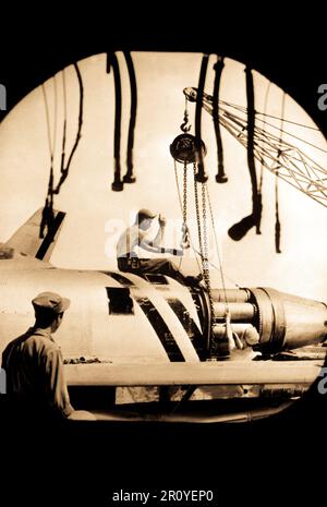 Una manutenzione aeromobili equipaggio dell'U.S. Forze Aeree 4° Fighter-Interceptor ala in Corea, fotografata attraverso il tubo di un F-86 Sabre, paranchi un motore in posizione per l'installazione su uno dei jet da combattimento piani. Settembre 1951. Foto Stock