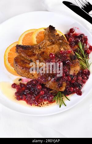 Braciole di maiale fritte servite con salsa ai mirtilli con arancia e rosmarino. Sono eleganti per un pranzo o una cena. Foto Stock