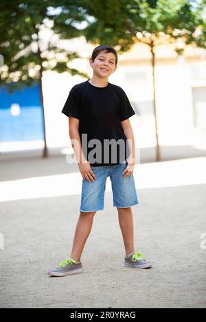 Teen in pantaloncini neri e t-shirt nera in piedi mentre si guarda la fotocamera Foto Stock