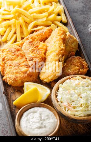 Il Fish Fry è accompagnato da coleslaw, patatine fritte, salsa tartara closeup sulla tavola di legno sul tavolo. Verticale Foto Stock