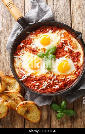 Uova in Purgatorio è un piatto italiano facile servito con un sacco di pane croccante per immergere il primo piano sul tavolo di legno. Vista verticale dall'alto Foto Stock