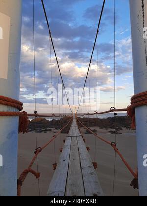 Una vista panoramica sul fronte spiaggia di un ponte di legno che si estende sulla costa sabbiosa Foto Stock