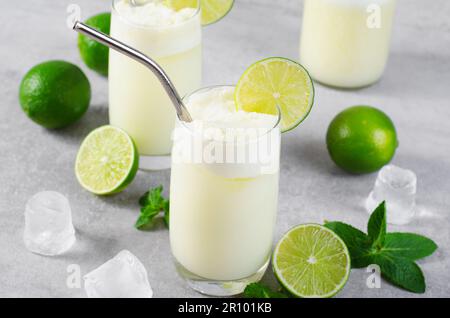 Limonata brasiliana, rinfrescante limonata cremosa o limeata con fettine di lime e menta su sfondo luminoso Foto Stock