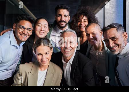 Allegro ritratto di gruppo di uomini d'affari che scattano una foto in ufficio guardando la fotocamera sorridente. Foto Stock