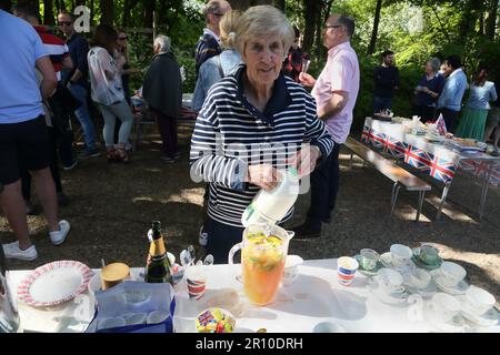 Donna anziana che fa il tè alla festa di strada che celebra il re Charles III incoronazione Surrey Inghilterra Foto Stock