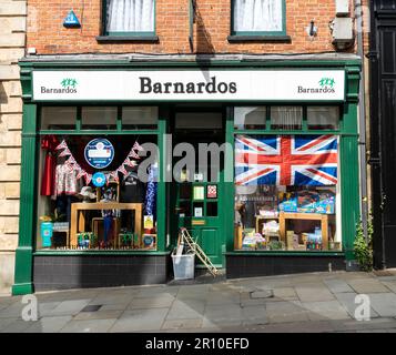 Barnardos negozio di beneficenza con bandiera sindacale e bunting che celebra l'incoronazione di re Carlo III High Street Lincoln City, Lincolnshire, Inghilterra, UK Foto Stock