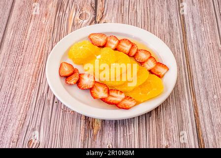 Un dessert fruttato con fette d'arancia sbucciate e fragole mature a fette Foto Stock